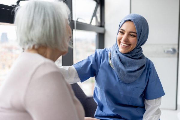 Muslim nurse talking to a senior patient at the hospital and smiling - healthcare and medicine concepts