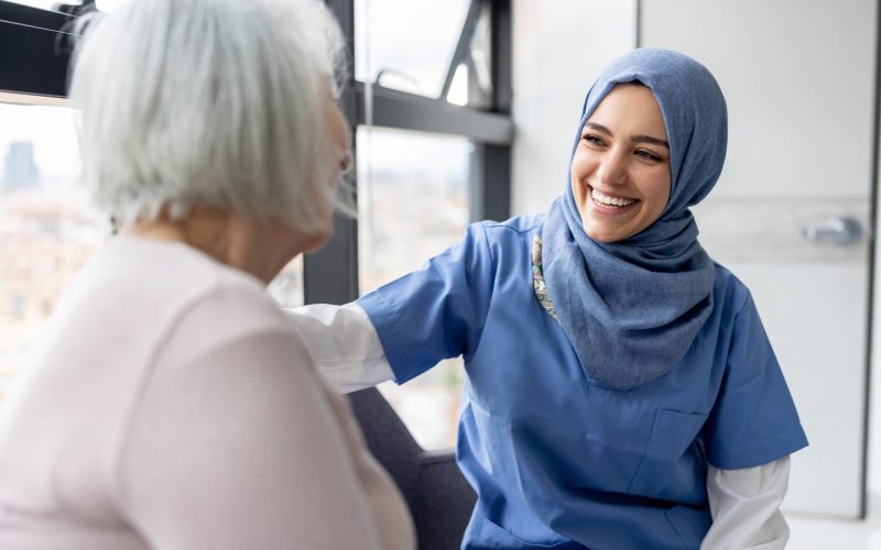Muslim nurse talking to a senior patient at the hospital and smiling - healthcare and medicine concepts