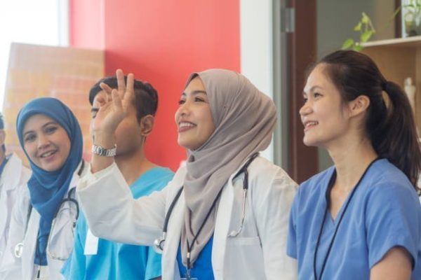 diverse medical team with different ethnic attending medical conference. Muslim female doctor raise hand in a meeting